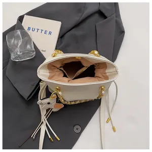 Detail of a quilted crossbody bag featuring chain handle, drawstring, and spacious interior