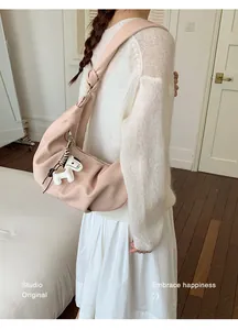 Detail of pink croissant underarm bag with a decorative horse charm and wide shoulder strap