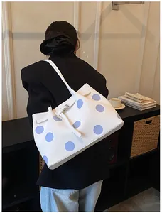 Dettaglio borsa a secchiello bianca a pois blu con cinturino decorativo fine