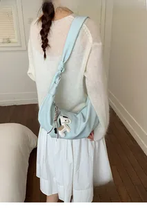 Detail of light blue hobo bag with knotted shoulder strap and dog charm accessory