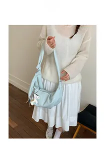 Detail of light blue hobo bag with knotted side and white horse charm accessory