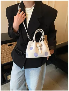 Dettaglio di una borsa tote bianca a pois viola, con fibbia in metallo e tracolla regolabile