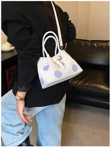 Dettaglio della borsa tote bianca a pois indossata con un blazer nero professionale