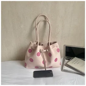 Dettaglio borsa tote rosa chiaro a pois con doppi manici sottili e trama in pelle sintetica