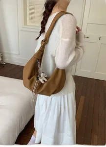 Brown leather crescent bag detail with silver hardware and a cute puppy keychain