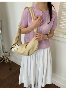 Detail of cream pleated crescent bag with a cute puppy charm and wide strap