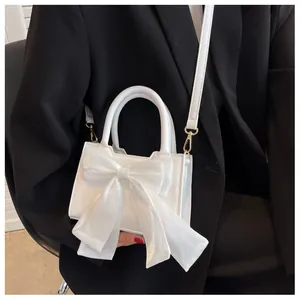 Close-up of white mini handbag with large organza bow detail and gold metal hardware