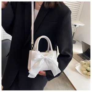Detail of white mini handbag featuring a large tulle bow and elegant top handle