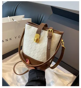 Gros plan détaillé du sac seau matelassé beige avec bordure en cuir brun et fermoir doré