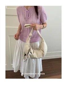 Chic off-white hobo bag with pleated design and pony charm shown on a model