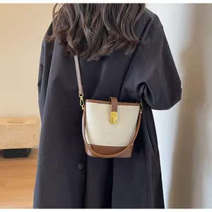 Détail du sac seau contrasté en cuir gaufré crème avec fermoir doré tournant