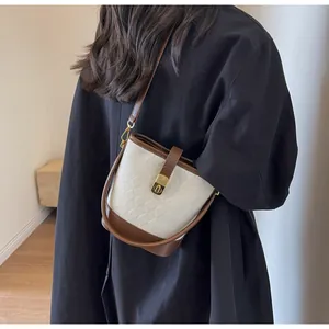 Détail du sac seau matelassé blanc avec garniture en cuir marron et fermoir doré