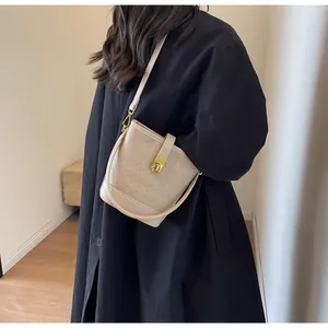 Détail du sac seau beige avec texture tressée, fermoir doré et bandoulière