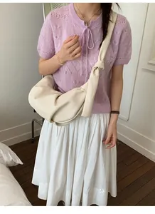 Detail of cream croissant bag featuring a stylish knotted shoulder strap and soft leather folds
