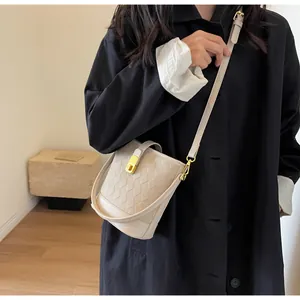Détail du sac seau beige avec texture gaufrée losange et boucle en métal doré