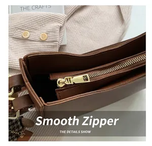 Detail view of smooth golden metal zipper and dark brown leather texture of the tote bag