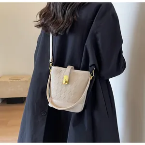 Détail du sac seau beige avec texture matelassée et élégant fermoir en métal doré brillant
