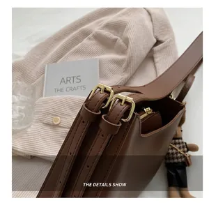 Close-up of adjustable brown leather straps with gold buckles and a cute bear charm
