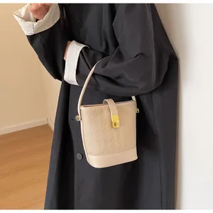 Détail du sac seau beige avec texture matelassée, fermoir doré et anse en cuir