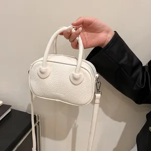 Dettaglio della borsa color crema in pelle PU con trama a rilievo e logo FASHION inciso