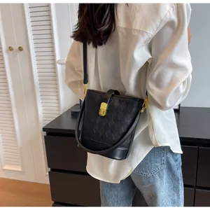 Détail d'un sac seau matelassé noir avec fermoir doré et bandoulière sur un mannequin