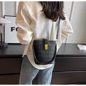 Détail du sac seau noir matelassé avec fermoir doré et bandoulière sur un mannequin