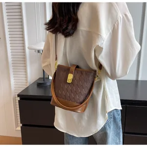 Détail du sac seau marron matelassé avec fermoir doré et empiècements en cuir lisse