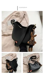 Detail of black faux leather crescent saddle bag with cute plush rabbit charm decoration