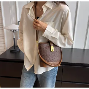 Détail d'un sac seau en cuir matelassé marron foncé avec boucle dorée et bandoulière réglable