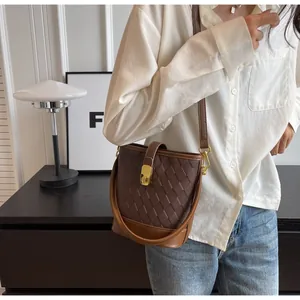 Détail du sac seau marron foncé avec texture matelassée et fermoir doré sur modèle