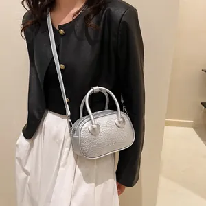 Mini borsa argento con trama coccodrillo e dettagli a cuore indossata da una modella