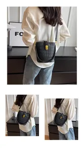 Détail d'un sac seau en cuir matelassé noir avec fermoir tournant doré et bandoulière
