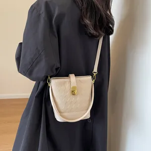 Sac seau matelassé beige minimaliste avec fermoir doré porté à l'épaule pour un style chic