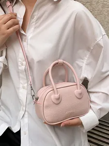 Borsa rosa effetto coccodrillo con dettagli a cuore e tracolla su camicia bianca