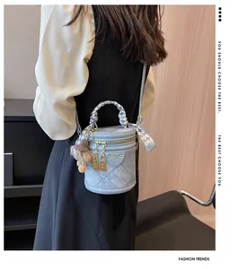 Detail of light blue denim quilted bucket bag with silk scarf handle and plush pendant