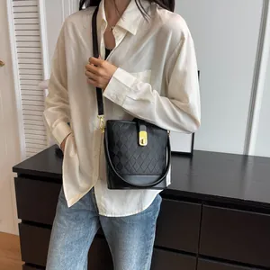 Sac seau noir matelassé avec fermoir doré et bandoulière porté par un mannequin