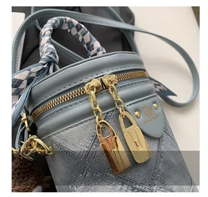 Detail of smooth gold metal zippers and silk scarf handle on light blue bucket bag