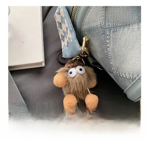 Macro detail of a plush cartoon monster charm on a light blue denim bucket handbag