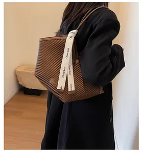 Detail of pleated brown tote bag featuring wide branded strap and fashion logo patch