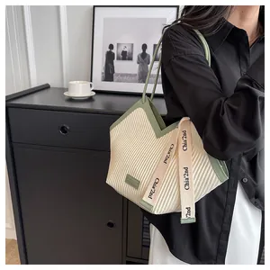 Detail of a pleated canvas tote bag with contrast cream and green wavy edge design