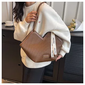 Brown pleated tote bag detail showing synthetic leather texture and fashion brand tag