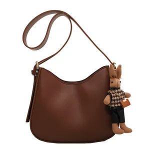 Minimalist dark brown crescent crossbody bag in matte leather with cute rabbit charm