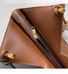 Detail of smooth gold zipper and leather knots on a large brown commuter tote bag
