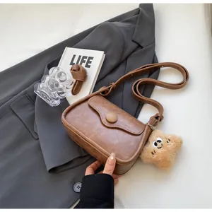 Detail of vintage brown textured PU leather bag with flap and yellow plush star charm