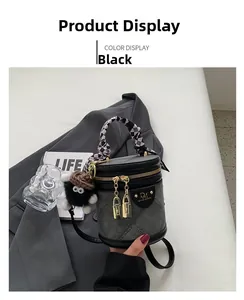 Close-up of black bucket bag featuring textured fabric, silk scarf handle, and plush charm