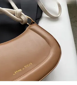 Détail du sac en cuir mat avec bandoulière nouée et boucle dorée élégante