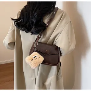 Brown retro crossbody square bag with plush smiley charm shown on a khaki trench coat