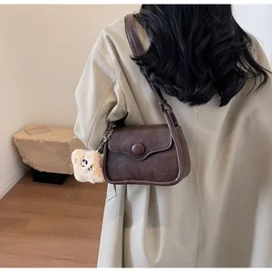 Deep brown retro crossbody bag featuring a round buckle and a cute beige plush charm detail