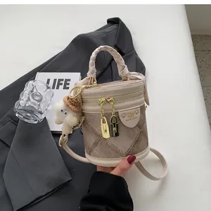Detail view of beige PU leather bucket bag with silk scarf handle and sheep plush charm