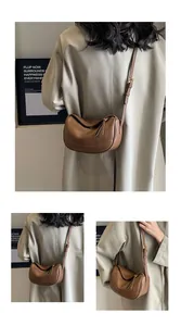 Detail of brown litchi pattern leather texture and zipper on half-moon crossbody bag